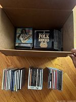 Open box showing assorted CDs including Folk Rewind Live and several rows of jewel cases