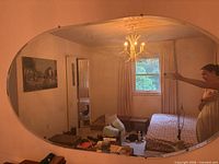 Full view of frameless oval mirror hung on wall