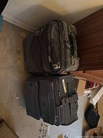 Two dusty soft-sided wheeled suitcases side by side