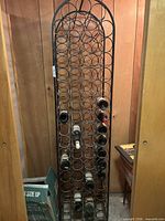 Full view of tall metal wine rack with bottles inserted