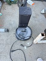 Robot vacuum docked on auto-empty clean base with power cord visible