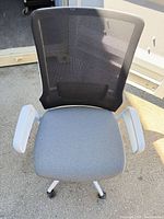 Front view of chair showing mesh back, gray seat, white arms and base