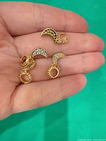 Four gold-plated crescent charms on hand for scale and detail