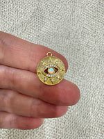 Front view of gold tone evil eye pendant with simulated opal and cubic zirconia