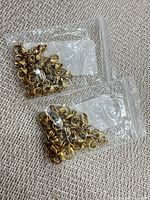 Two clear poly bags filled with gold tone lobster clasps