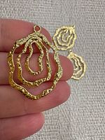 Close-up of one pendant showing textured concentric wavy rings and hanging loop