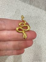 front view of gold-tone snake pendant, showing rhinestone eyes and loop bail