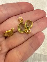 Close-up of charms in hand showing stone cut, bezel and loops