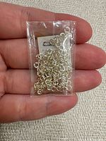 Sealed plastic bag of silver jump rings in hand