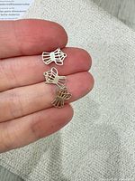 Three charms on fingertip showing scale and design