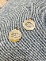 Front view of both sterling silver evil eye charms on denim