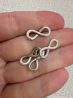Three sterling silver infinity charms in hand