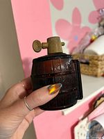 Front view of amber glass barrel atomizer held in hand