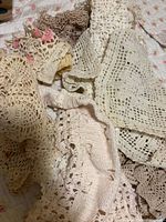 Pile of assorted cream, ivory and beige crochet doilies showing quantity and mixed patterns
