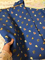 Fabric laid flat showing blue background and multicolour stepped square motifs