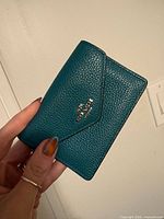 Front view showing Coach logo and pebbled teal leather