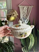 Side view of lidded casserole showing fruit decals, speckled glaze, handles, knob finial