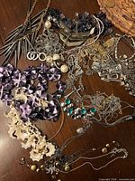 Overview of mixed jewelry pieces including spiked necklace, purple disc beads, shell beads, multiple chains