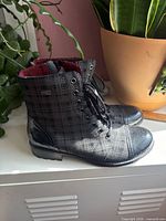 Side view of both boots showing black plaid exterior, laces, side zipper, heel and overall condition