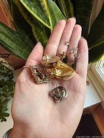 Assortment of nine single earrings in palm, showing variety of styles and finishes