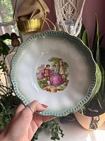 Top view showing bowl design, scalloped green rim, gilding, and central couple scene