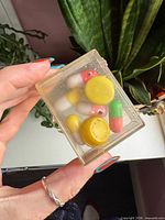 Front view of clear box showing capsule toys, yellow disc and overall contents