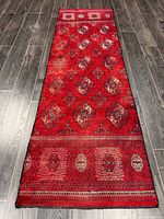 Full view of red Turkman runner rug showing geometric gul motifs and borders