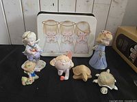 Group shot of all items including Precious Moments tin, various figurines, turtles and bell