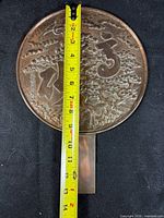 Round bronze mirror back with relief motifs measured with tape