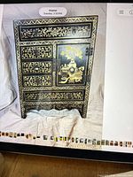 Front view of black and gold lacquer chest showing drawers and door
