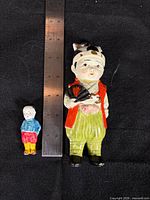 Both figurines beside ruler showing relative sizes and details