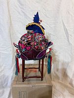 Front view of embroidered child's hat on stand showing floral embroidery and tassels