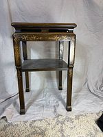 Front view of two-tier chinoiserie side table showing gilt decoration and overall condition