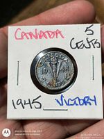 Reverse side showing V with torch and date 1945 in flip