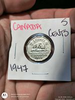 Reverse side of coin in holder with handwritten year and denomination