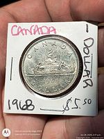 Front of 1968 Canada dollar in holder showing Voyageur reverse