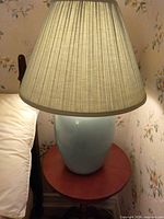 Lamp on bedside table showing full view of base and shade illuminated