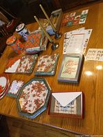 Overview of lot showing paper plates, napkins, greeting cards, candles with holders, metal tins and sticker sheets