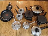 Group shot showing stacked T-fal pans, stainless saucepans, black pots and lids