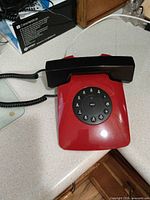Full view of red base with black handset showing circular push-button dial