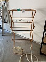 Full view of wooden drying rack and portable vacuum motor with hose and wand on floor