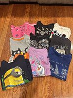 All ten shirts folded and grouped on wood floor