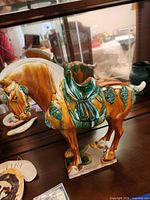 Left side view of glazed pottery horse on shelf