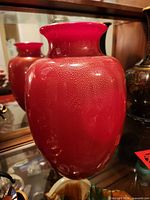 Full view of red crystal vase on display shelf