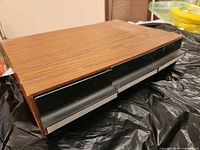 Closed wooden cassette storage box showing top woodgrain finish and drawer fronts