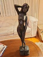 Front view of wooden female nude statue on table
