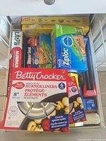 Drawer containing multiple boxed food-storage items and burner liners