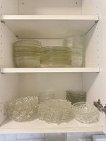 Stacks of clear glass bowls and plates on cabinet shelves