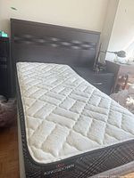 Bed showing headboard, mattress and side of metal frame