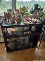 Front view of dark wood three-shelf bookcase with decorative items on shelves (contents not included)